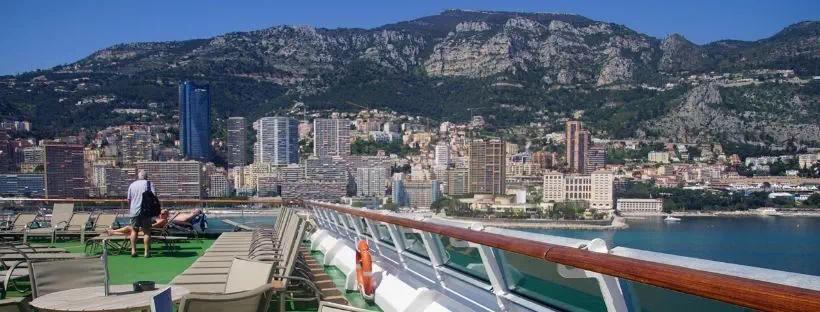 Vue du ponton d'un navire de croisière : côte, ville et montagnes