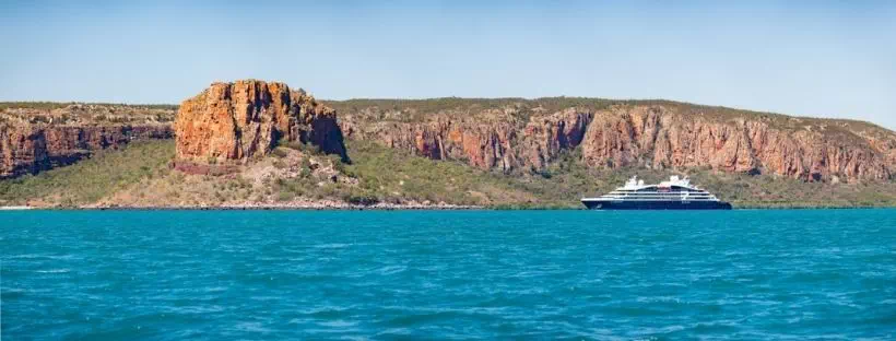 Un navire de la flotte Ponant navigue sur la mer bleue avec des côtes anguleuses