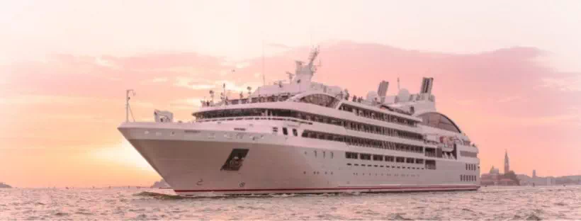 Le bateau Lyrial de Ponant navigue sur la mer Méditerranée devant un ciel rose