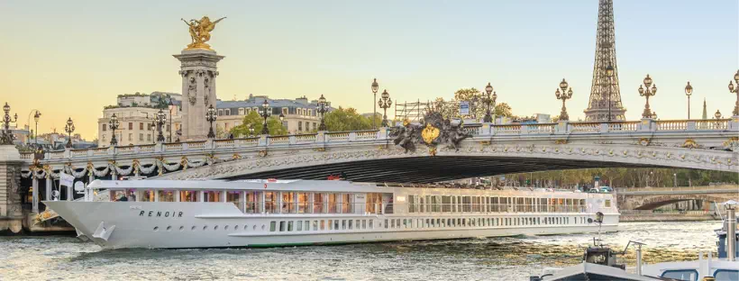 navire de croisière voguant sur un fleuve avec un couché de soleil