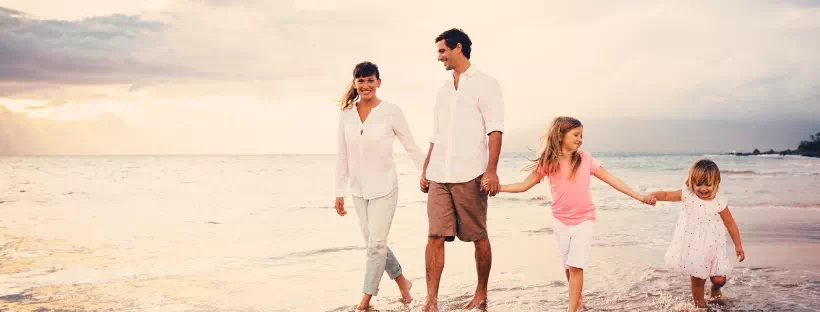 Photo d'une famille, parents et 2 jeunes enfants se baladant au bord de mer