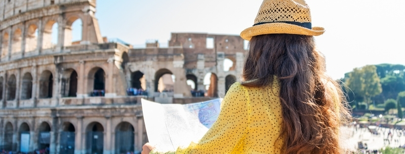 Femme de dos avec une carte pour se localiser, faisant face au Colisée à Rome