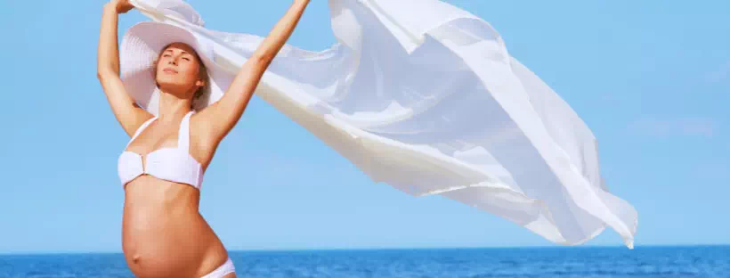 Femme qui regarde son ventre sur une plage 