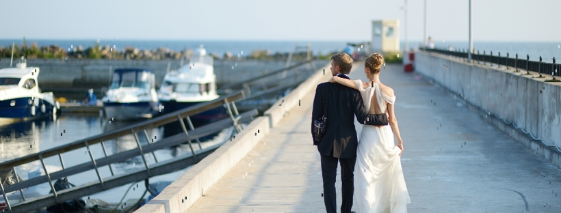 Couple de mariés de dos, marchant le long d'un port