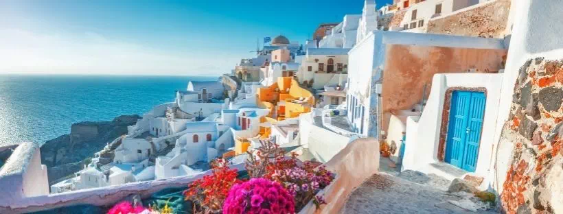 Vue depuis le haut du village de Santorin avec des fleurs roses et des maisons oranges blanches et b