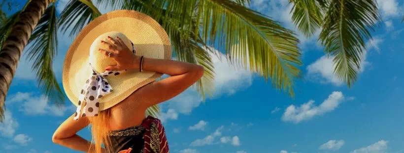 Femme de dos avec un grand chapeau regardant la mer sur une plage 