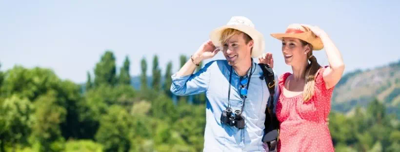 couple de vacanciers tout sourire qui regarde en direction de l’horizon vers la gauche