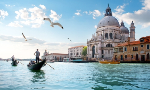 Photo de Venise en Italie avec gondoliers naviguant, ainsi que des habitations et monuments